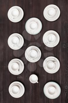 food concept - top view of many white cups and saucers on dark brown table