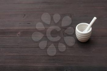 food concept - white ceramic cup for sake with spoon on dark brown wooden board