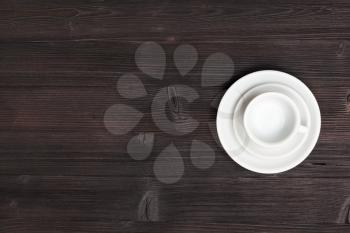 food concept - above view of one white cup with saucers on dark brown table