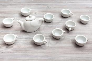 food concept - many white ceramic cups and teapot on gray brown table