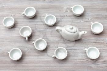 food concept - top view of many white ceramic cups and teapot on gray brown table