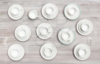 food concept - top view of many white cups and saucers on gray brown table