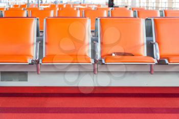 empty orange seat in departure lounge of airport