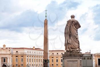 travel to Italy - view of statue the Apostle Peter and obelisk with cross on Saint Peter's Square (Piazza San Pietro) in Vatican city in evening