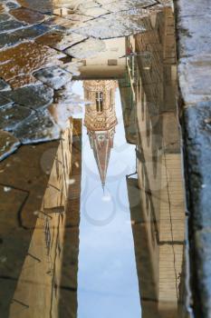 travel to Italy - bell tower of church Badia Fiorentina reflected in puddle after rain in Florence city