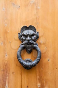travel to Italy - ancient male head knocker on old wood door in Florence city