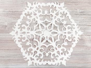 above view of snowflake cut out of paper on light brown wood table