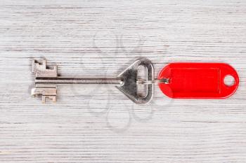 big door key with red blank keychain on wooden table