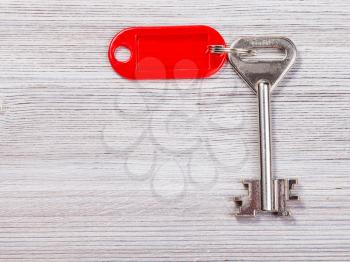 big door key with red blank key chain on wooden board