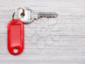 door key with red blank key chain on wooden background