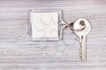door key with white blank key chain on wooden board
