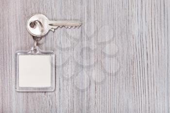 door key with white blank key chain on wooden background