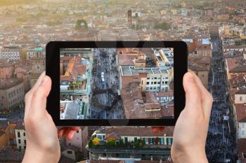 travel concept - tourist photographs street in Bologna city on tablet in Italy
