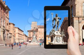 travel concept - tourist photographs fountain of Neptune in Bologna city on tablet in Italy