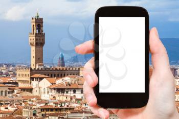 travel concept - tourist photographs Florence town with Palazzo Vecchio on smartphone with cut out screen with blank place for advertising in Italy