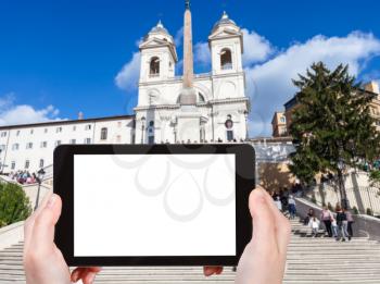 travel concept - tourist photographs Church Santissima Trinita dei Monti and Spanish Steps in Rome city on tablet with cut out screen with blank place for advertising in Italy