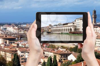 travel concept - tourist photographs vasari corridor from Arno River in Florence city on tablet in Italy
