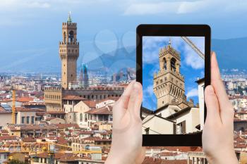 travel concept - tourist photographs tower of Palazzo Vecchio in Florence city on tablet in Italy