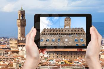 travel concept - tourist photographs facade of Palazzo Vecchio in Florence city on tablet in Italy
