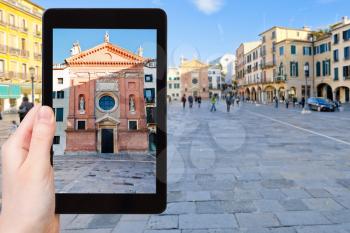 travel concept - tourist photographs church San Clemente on piazza dei Signori in Padua city on tablet in Italy