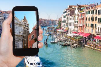 travel concept - tourist photographs buildings in Venice city on smartphone in Italy