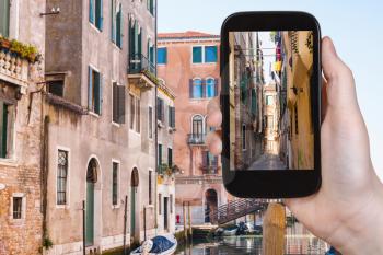 travel concept - tourist photographs narrow street in Venice city on smartphone in Italy