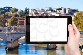 travel concept - tourist photographs bridge on Tiber River in Rome city on tablet with cut out screen with blank place for advertising in Italy
