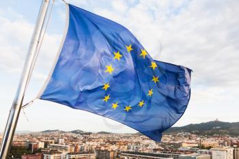 european union flag flutters above Barcelona city