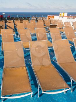 many empty sunbathing chairs on deck of cruise liner