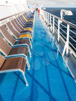 row of empty sunbathing chairs on deck of cruise liner