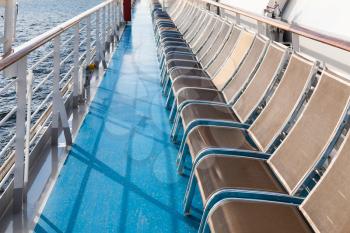 row of sunbathing chairs on deck of cruise liner