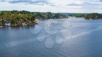 panorama of Baltic Sea coastline with villages in green woods, boats in fiord autumn evening, Sweden