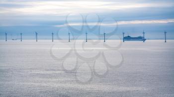 Travel to Denmark - cruise liner near offshore wind farm Middelgrunden in Oresund near Copenhagen city in Baltic Sea in blue autumn morning