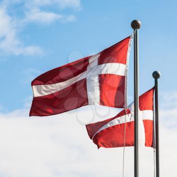 Travel to Denmark - two danish flags fluttering in wind in Copenhagen city in autumn day