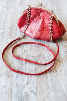small red leather women's handbag on wooden boards
