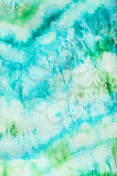 textile background - abstract blue and green pattern dyed on fabric in nodular batik technique close up