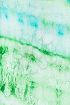 textile background - abstract blue and green pattern dyed on silk in nodular batik technique close up