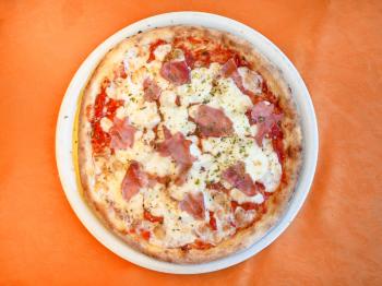 travel to Italy, italian cuisine - above view of pizza with prosciutto on plate in Sicily