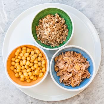 top view of various cold breakfast cereals in bowls on white plate