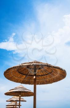 travel to Italy - straw parasols and blue sky on San Marco beach in Sicily