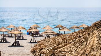 travel to Italy - straw parasols on San Marco beach on Ionian Sea coast in Sicily