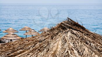 travel to Italy - straw parasols on marina di cottone beach on Ionian Sea coast in Sicily