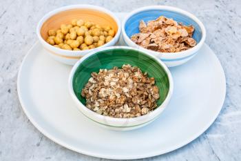 three bowls with cold breakfast cereals on white plate