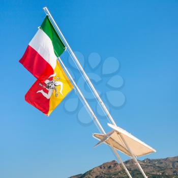 travel to Italy - Italian and Sicilian flags flutter by wind and blue sky in Sicily