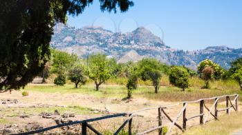 travel to Italy - view of ruins in Naxos Archaeological Park in Giardini Naxos town and Taotmina city on mountain in Sicily