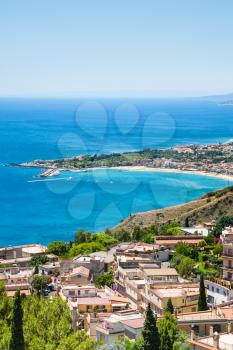 travel to Italy - view of Taormina city and giardini naxos beach on the coast of Ionian sea from Castelmola village in Sicily in summer day