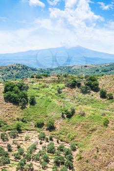 travel to Italy - green mountain slope and Etna mount near Calatabiano town in Sicily