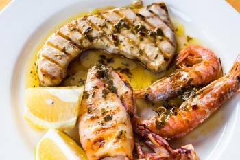 travel to Italy, italian cuisine - sicilian grilled fish and seafood mix on white plate close uo in Sicily