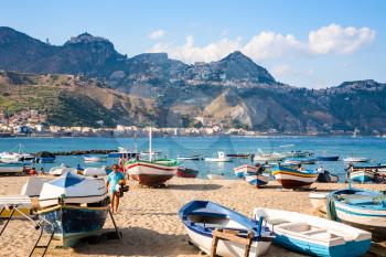 GIARDINI NAXOS, ITALY - JULY 6, 2011: people near boats on beach in Giardini Naxos town. Naxos was founded by Thucles the Chalcidian in 734 BC, and since 1970s it has become a seaside-resort