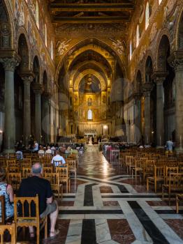 MONREALE, ITALY - JUNE 25, 2011: visitors in interior Duomo di Monreale in Sicily. The cathedral of Monreale is one of the greatest examples of Norman architecture, it was begun in 1174